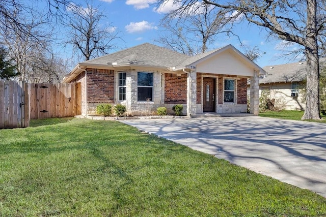 view of front facade featuring brick siding, a shingled roof, stone siding, fence, and a front yard