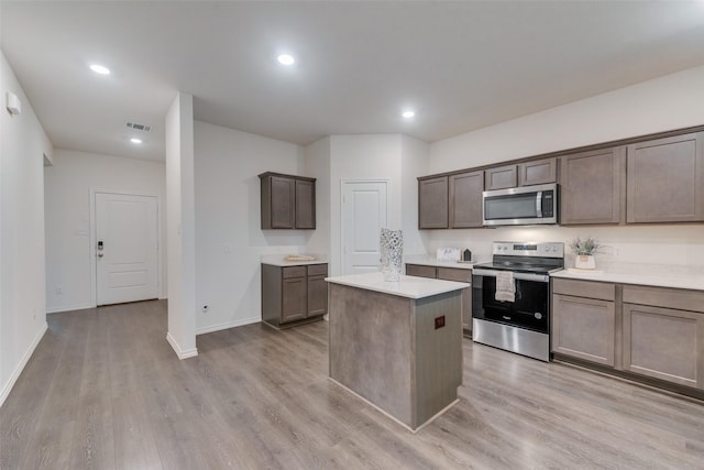 kitchen with light hardwood / wood-style flooring, a kitchen island, and appliances with stainless steel finishes