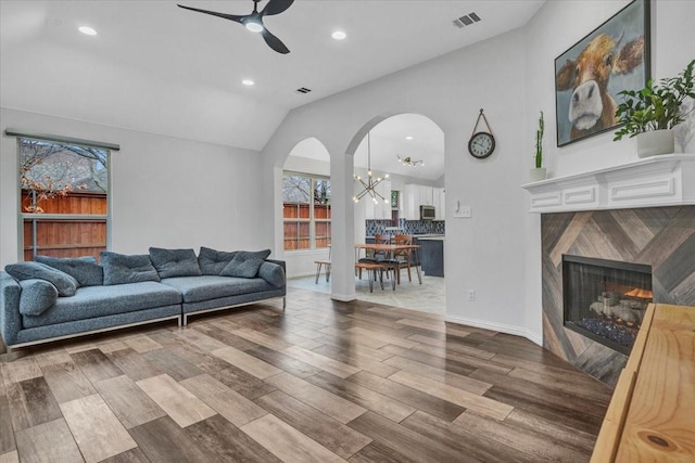 living room with lofted ceiling, ceiling fan with notable chandelier, and light hardwood / wood-style floors