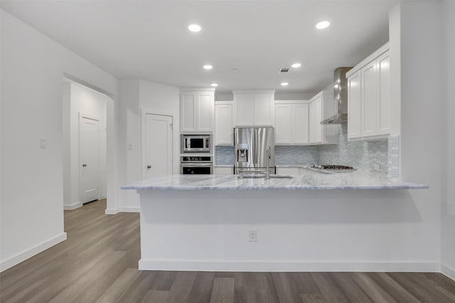 kitchen featuring appliances with stainless steel finishes, light stone countertops, white cabinets, decorative backsplash, and kitchen peninsula