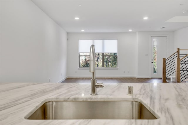 kitchen with light stone countertops, sink, and hardwood / wood-style floors