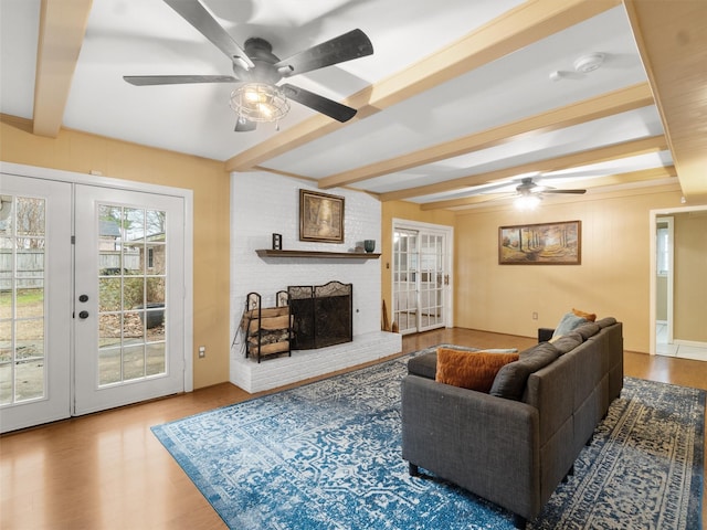 living room with wood-type flooring, a fireplace, beam ceiling, and french doors