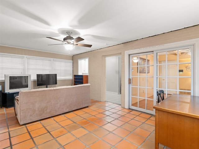 living room with light tile patterned floors, ceiling fan, and brick wall