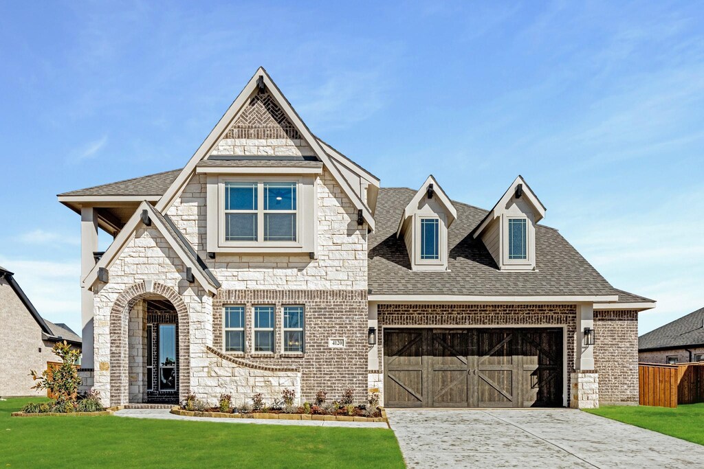 view of front of home with stone siding, a shingled roof, a front lawn, and driveway