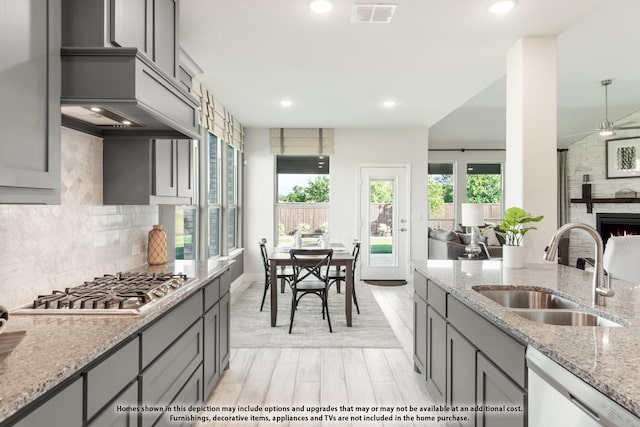 kitchen with appliances with stainless steel finishes, sink, gray cabinetry, and light stone counters