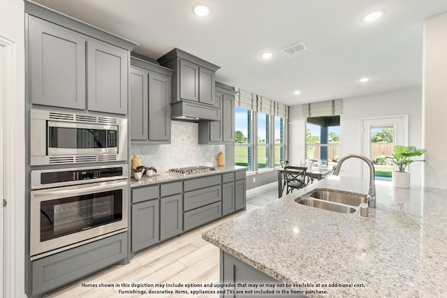 kitchen featuring sink, gray cabinets, light stone countertops, and appliances with stainless steel finishes