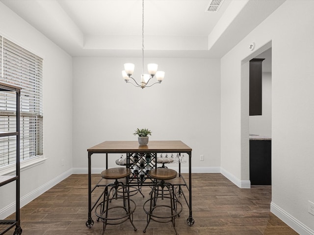 dining space with a chandelier, dark hardwood / wood-style flooring, and a tray ceiling