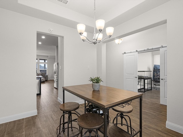 dining room featuring a raised ceiling, a barn door, dark hardwood / wood-style floors, and an inviting chandelier