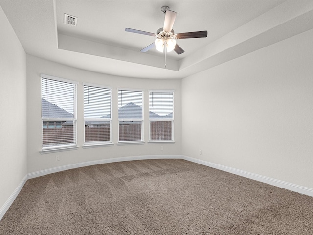 carpeted empty room with a tray ceiling and ceiling fan