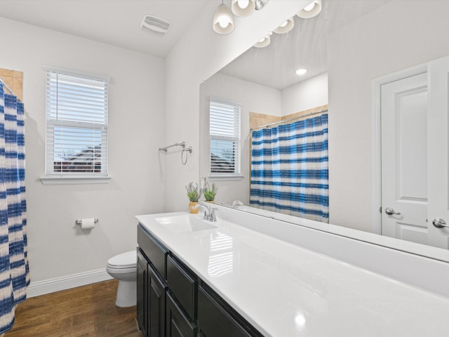 bathroom featuring hardwood / wood-style flooring, vanity, toilet, and curtained shower