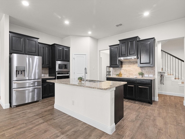 kitchen with a kitchen island with sink, sink, dark hardwood / wood-style flooring, and appliances with stainless steel finishes