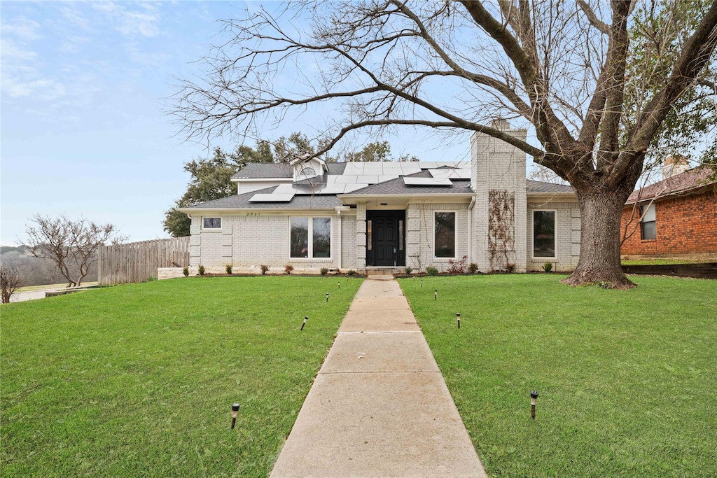 view of front of property with a front yard and solar panels