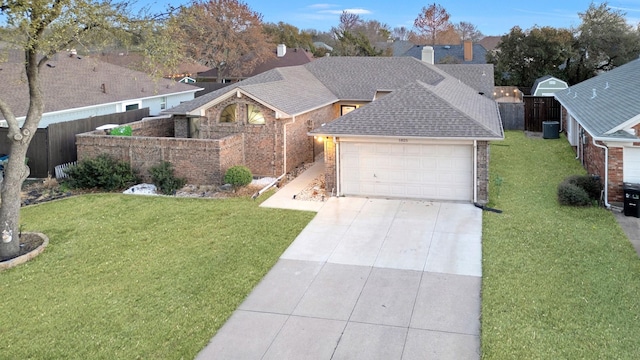 view of front facade with roof with shingles, concrete driveway, a front yard, and fence