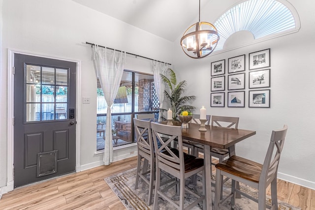 dining room with a chandelier, plenty of natural light, light wood-style flooring, and vaulted ceiling