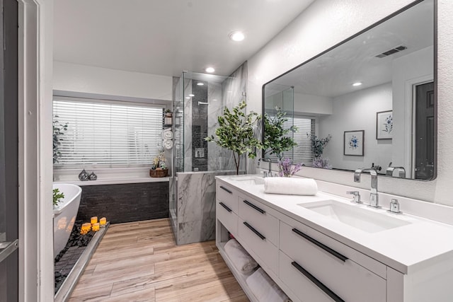 full bath featuring a shower stall, a freestanding tub, visible vents, and a sink