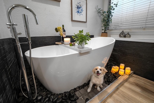 bathroom with a textured wall and a freestanding tub