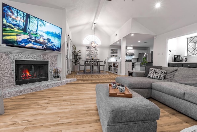 living area featuring light wood finished floors, a brick fireplace, beamed ceiling, recessed lighting, and high vaulted ceiling