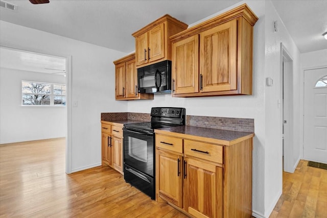 kitchen featuring dark countertops, ceiling fan, light wood-style flooring, visible vents, and black appliances