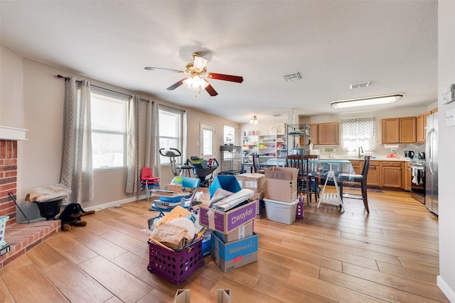 living room with ceiling fan, a healthy amount of sunlight, light hardwood / wood-style flooring, and a textured ceiling