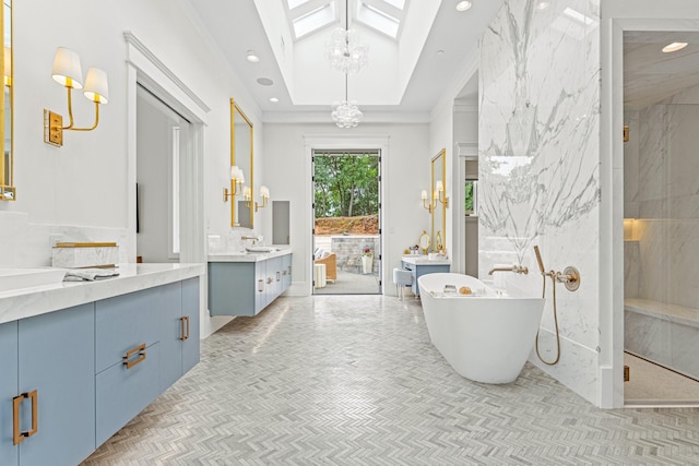 bathroom with an inviting chandelier, a skylight, vanity, a tray ceiling, and shower with separate bathtub