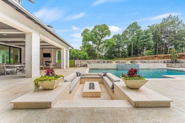 view of swimming pool featuring a patio, pool water feature, and an outdoor living space with a fireplace