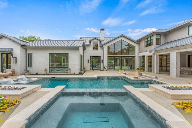 back of property with a pool with hot tub, a patio area, and an outdoor fire pit