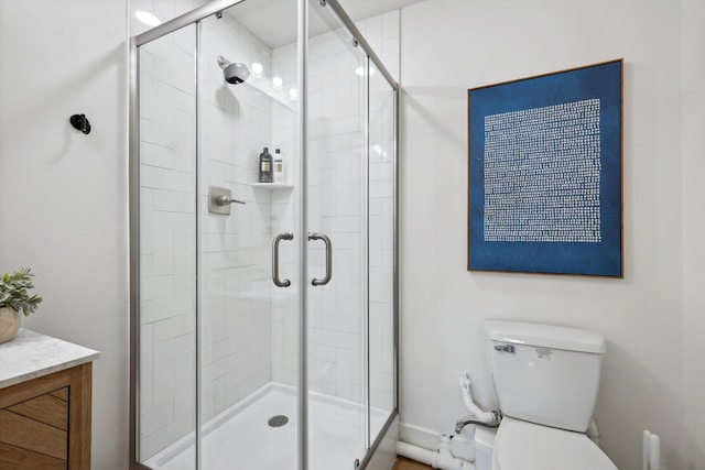 bathroom with an enclosed shower, vanity, and toilet