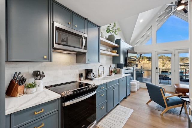 kitchen with lofted ceiling, sink, tasteful backsplash, appliances with stainless steel finishes, and light hardwood / wood-style floors