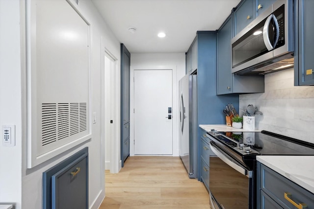 kitchen featuring tasteful backsplash, blue cabinetry, light hardwood / wood-style floors, and appliances with stainless steel finishes