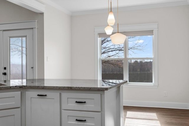 kitchen with plenty of natural light, dark stone countertops, decorative light fixtures, and white cabinets