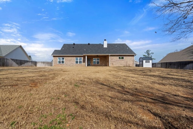 rear view of property featuring a lawn and a storage unit