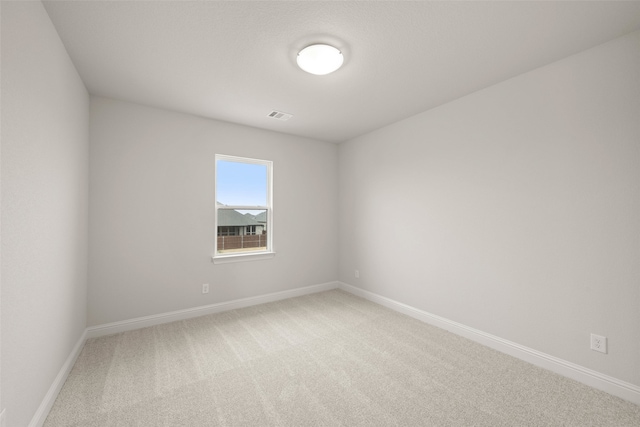 carpeted spare room featuring visible vents and baseboards