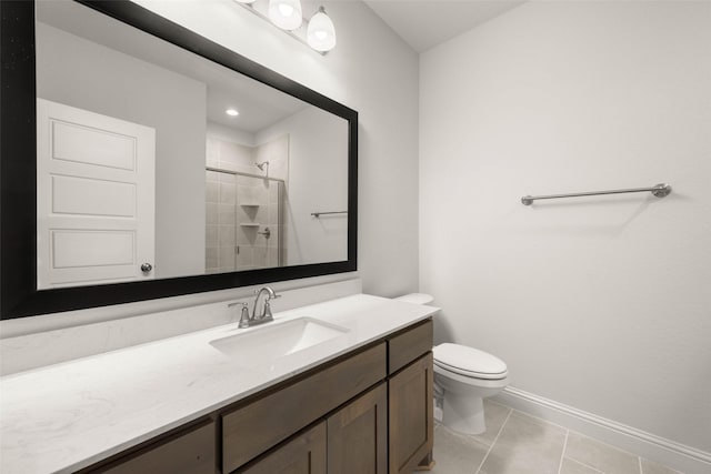 bathroom featuring tile patterned flooring, toilet, vanity, baseboards, and a stall shower