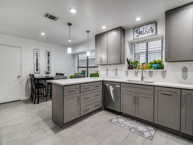 kitchen with pendant lighting, sink, gray cabinetry, stainless steel dishwasher, and kitchen peninsula