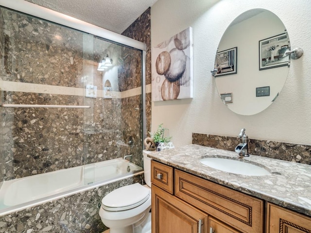 full bathroom featuring vanity, toilet, shower / bath combination with glass door, and a textured ceiling