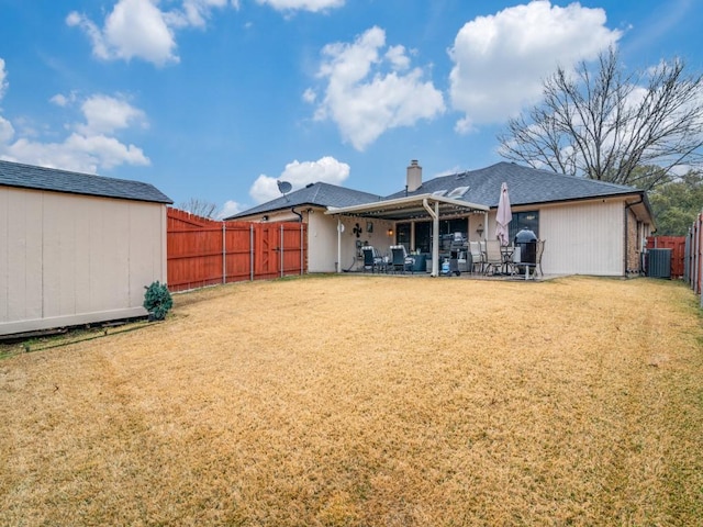 back of property with central AC, a patio, and a lawn