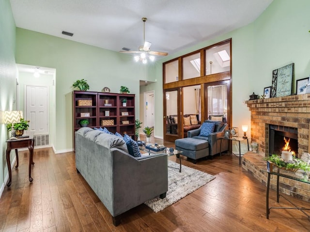 living room featuring wood-type flooring, a brick fireplace, ceiling fan, and high vaulted ceiling