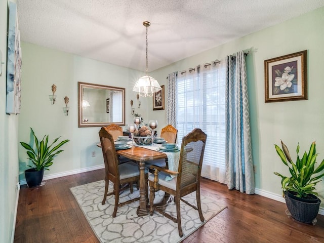 dining room featuring dark wood-type flooring and a textured ceiling