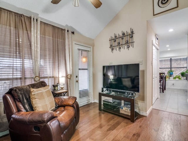 living room with vaulted ceiling, ceiling fan, and light wood-type flooring