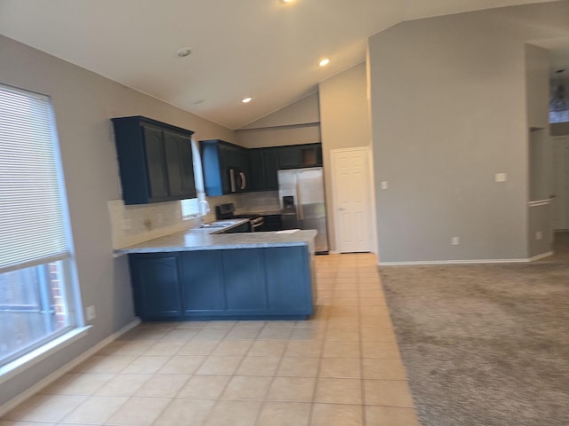 kitchen featuring sink, high vaulted ceiling, light tile patterned floors, kitchen peninsula, and stainless steel appliances