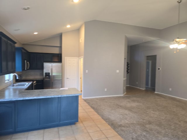 kitchen with lofted ceiling, sink, appliances with stainless steel finishes, light colored carpet, and kitchen peninsula