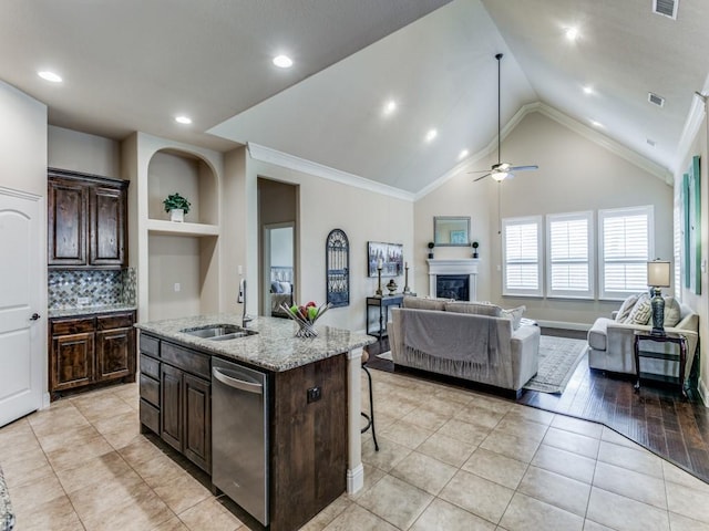 kitchen with a sink, open floor plan, dishwasher, and a glass covered fireplace