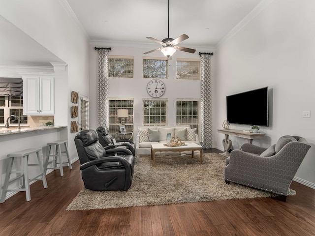 living room with dark hardwood / wood-style floors, a towering ceiling, sink, ornamental molding, and ceiling fan