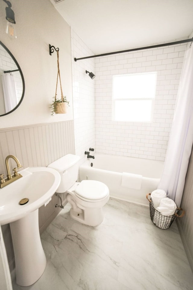 bathroom with shower / bathtub combination with curtain and toilet