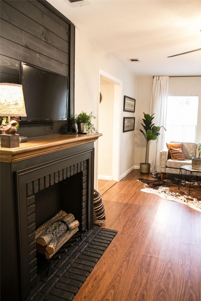 living area featuring a brick fireplace and hardwood / wood-style flooring