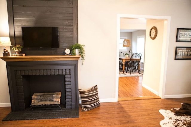 living room featuring a brick fireplace and wood-type flooring