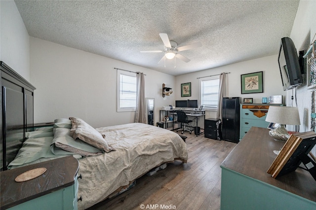 bedroom featuring hardwood / wood-style flooring, ceiling fan, multiple windows, and a textured ceiling