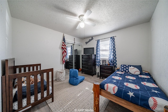 bedroom featuring ceiling fan, wood-type flooring, a closet, and a textured ceiling