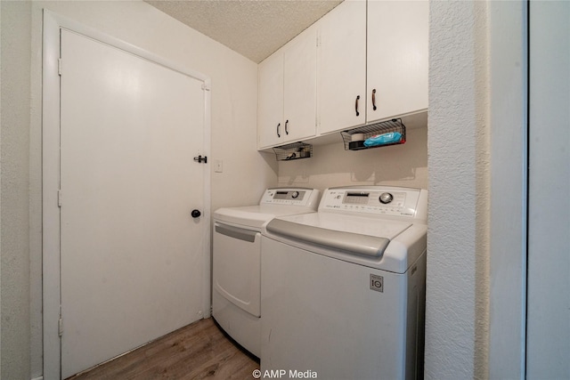 laundry area with hardwood / wood-style flooring, cabinets, washer and dryer, and a textured ceiling