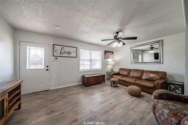 living room featuring hardwood / wood-style flooring, ceiling fan, and a textured ceiling